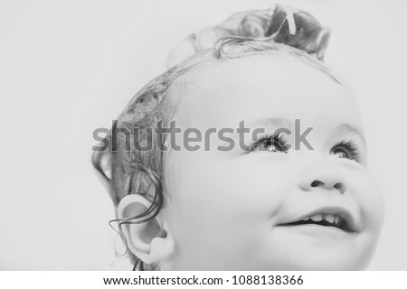 Portrait of small cute male kid with wet hair in bathroom smiling looking away on white background closeup, horizontal picture