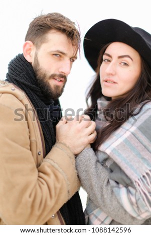 Portrait of american man and woman holding hands and wearing scarf and hat in white background. Concept of feelings and romantic love, winter photo session.