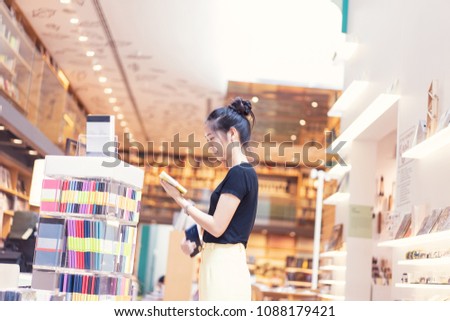 A girl is choosing a book and notebook at the bookstore in department store.