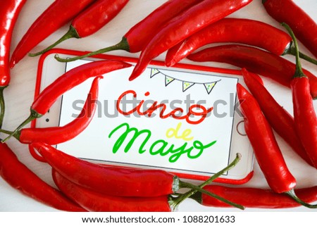 Cinco de Mayo decoration. Phone and red hot chili peppers closeup lying on white wooden background