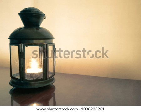 Burning candle in a metal lantern in a dark room