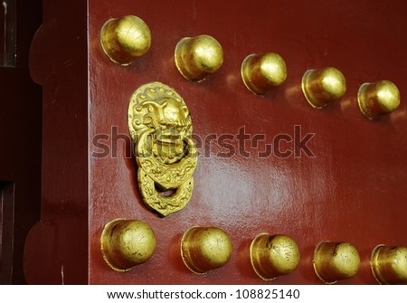 Picture of Chinese traditional ancient lion style knocker on red wood door.