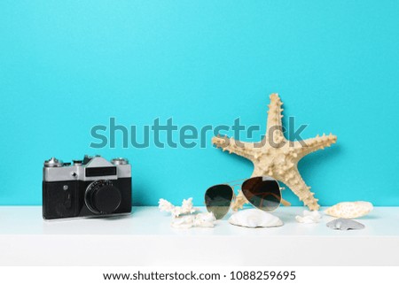 Starfish and old photocamera on white table against the blue wall. Mockup with copy space.