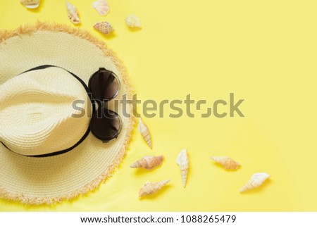 Straw beach foman's hat and black sun glasses with seashells on yellow background. Top view. Flat lay. Copy space. Trendy color Illuminating of the 2021 year.