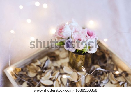A tender vase with flowers. Garland. A wooden tray.