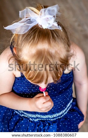 Top view on cutle little blond girl with her lollypop.
