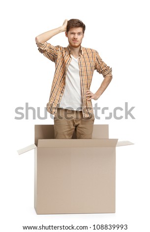 Young man wonders why he is inside the box, isolated, white background