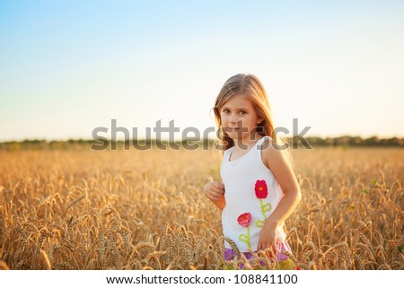 happy cute girl playing  in the wheat field on a warm summer day