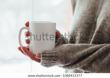 Close up of women's hands holding white mug with blank copy space scree for your advertising text message or promotional content, sweet coffee or tea. Royalty-Free Stock Photo #1088412377