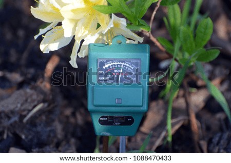 Soil moisture, light and PH meter for small private garden.Rhododendron  flowers as background 