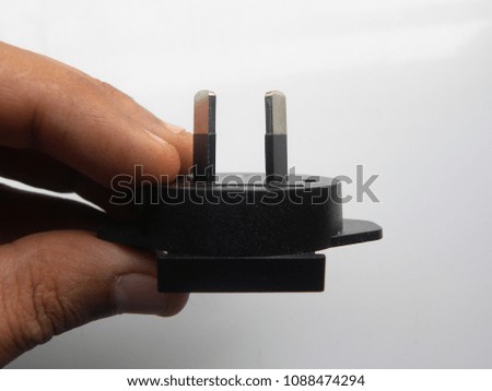 Hand of man holding black color 2 pin power plug adapter on white background