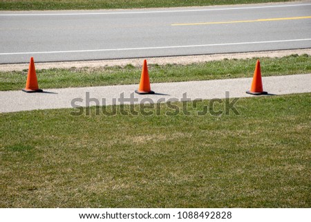 row of orange fluorescent traffic cones on sidewalk