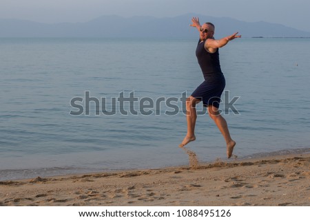 A man is jumping in the water at sea