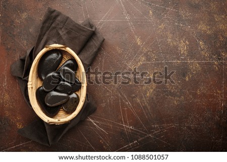 Zen stones in a wicker bowl in Asian style on a cinnamon old background