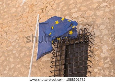 European union flag in the background the window of a medieval castle

