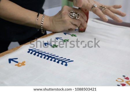 The process of creating a picture on the fabric. The hands of a talented artist create a pattern.