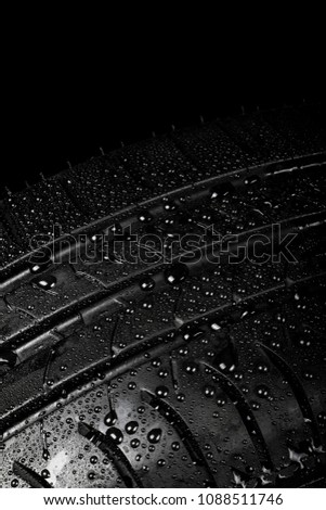Close up view of a car tyre isolated on a black background with water drops