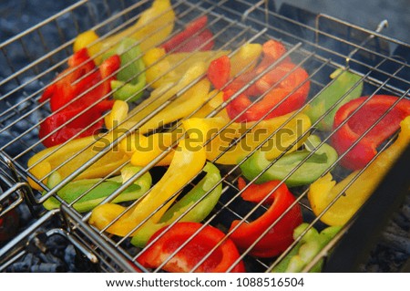 Red, yellow and green bell peppers cut into pieces, on a grid for grilling over hot coals. Barbecue for a vegetarian.
