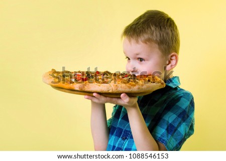 funny boy eating a big pizza on a bright yellow background