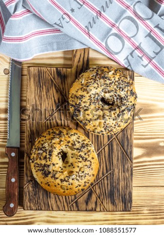 Fresh bread bagel with seed on wooden cutting board. Russian traditional bakery product. Top view