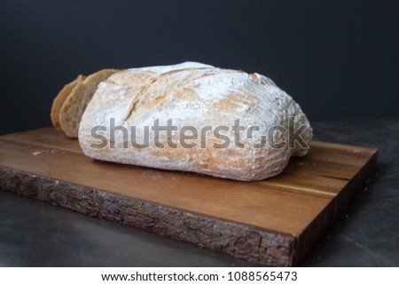 Isolated loaf of bread on a wooden board over a dark background