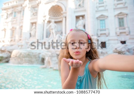Adorable little girl taking selfie by the Fountain of Trevi in Rome. Happy kid enjoy her european vacation in Italy