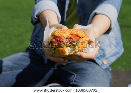 Hamburgers - street food . Burger in a female hand . Close-up.