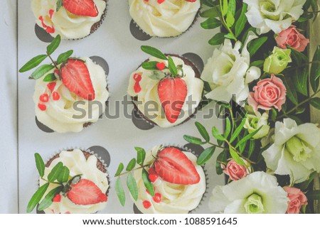 Tasty beautiful cupcakes in a box. Cupcakes decorated with strawberry, beads and real flowers. Small beautifull cakes. Romantic gift. Sweet dessert. Top view