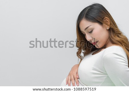 A pregnant woman in white dress stand pose for take a picture on white background