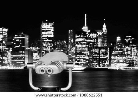 Black and white picture of binoculars pointed at Manhattan skyline at night, New York City, USA.