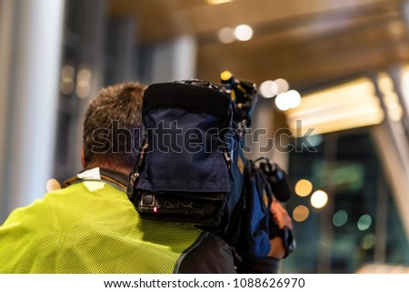 Back view cameraman filming news indoors