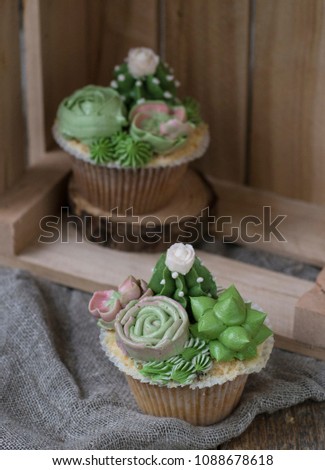 Capcakes decorated with creamy succulents on a wooden background