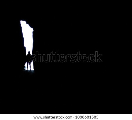 A person standing in a hole in a black cave in New Zealand