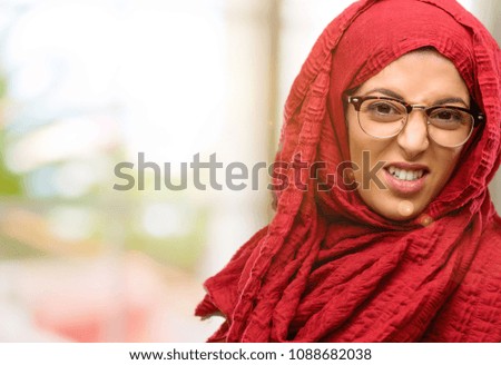 Young arab woman wearing hijab angry and stressful frowns face in dissatisfaction, irritated and annoyed, expressing anger