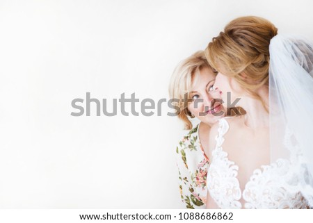 Mom congratulates the brides with a marriage and hugs. woman welcomes. Mom hugs her daughter. In the background a light wall  Royalty-Free Stock Photo #1088686862