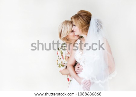 Mom congratulates the brides with a marriage and hugs. woman welcomes. Mom hugs her daughter. In the background a light wall  Royalty-Free Stock Photo #1088686868