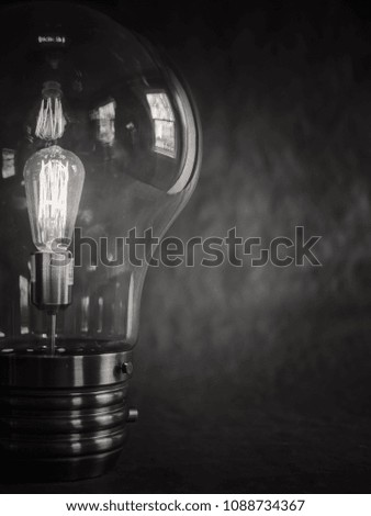 Black and White Close Up Partial Viewpoint/Composition Light Bulb/Lightbulb Against a Plain Black Background, Copy/Text Space at Right 
