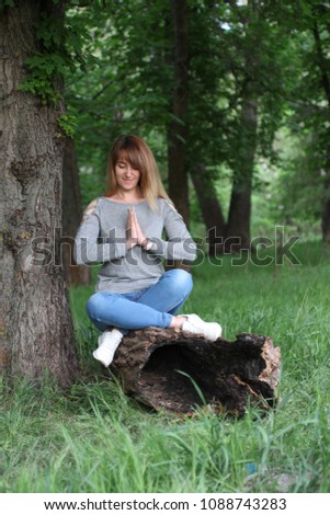 the girl is sitting in a lotus pose outdoors
