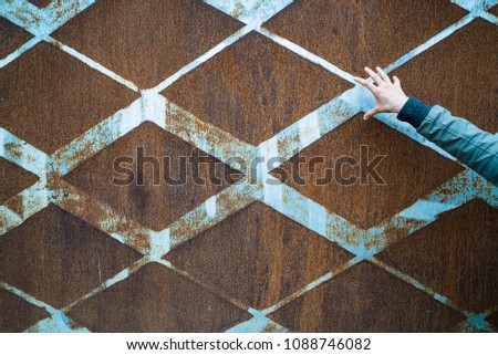 background of rusted vintage metal with a diamond pattern and vintage blue paint and a slender open female hand