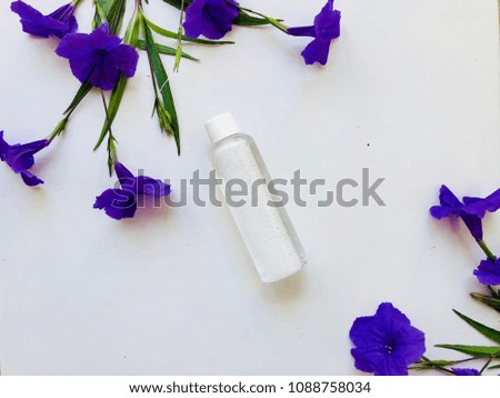 Empty perfume bottle with blue flowers on white background