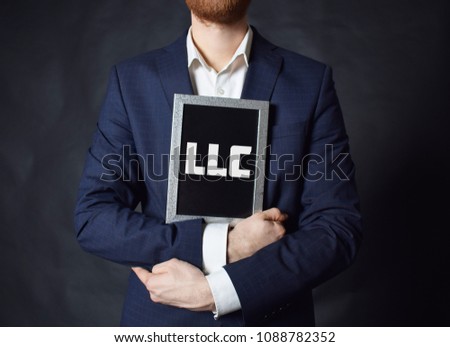 In the hands of a businessman a frame with the inscription:LLC
