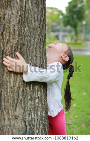Asian kid girl hugging a tree. Save the world concept.