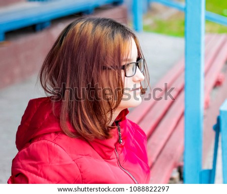 Brunette girl with glasses on the street in a red jacket