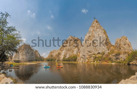 view of tourist relax in the small boat floating in the reservoir with rock mountain and blue sky background, Khao Ngu Stone Park,  Ratchaburi, Thailand