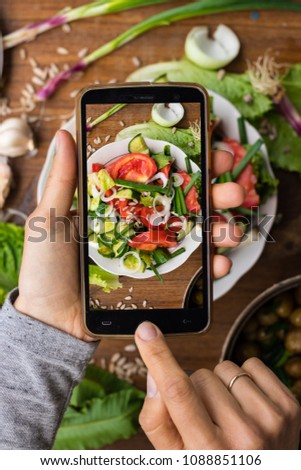 Phone photography of food. Woman hands take photo of lunch with smartphone for social media. Fresh vegetables Greek salad. Raw vegan vegetarian healthy dinner 