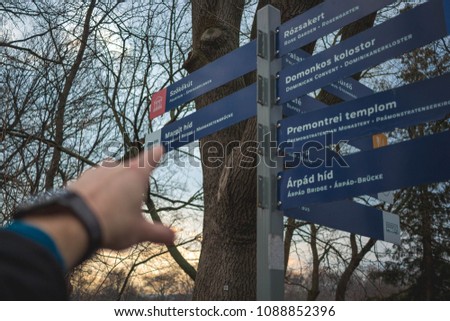 Choose your way! Young man pointing at a signpost. He is in Budapest, Hungary on Margaret Island.