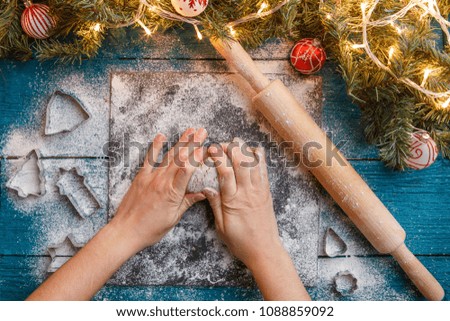 Photo of human hands, rolling pin, dough, spruce branches, garlands