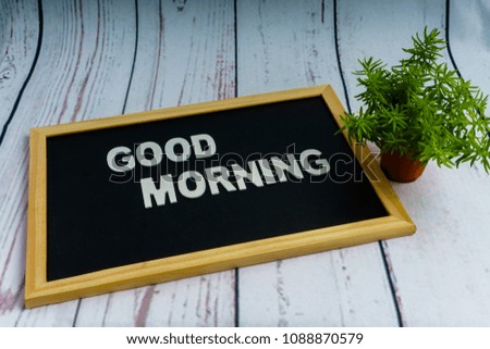 A concept image with words "GOOD MORNING" on the blackboard and small tree as decoration.