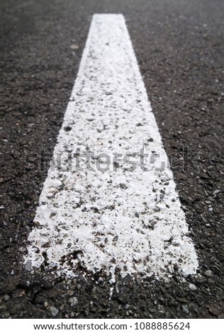Close-up of a white mark on the dark asphalt of the road.