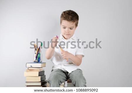 Young student sits on the books and holds pen for writing